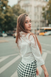 Portrait of young woman standing on street in city