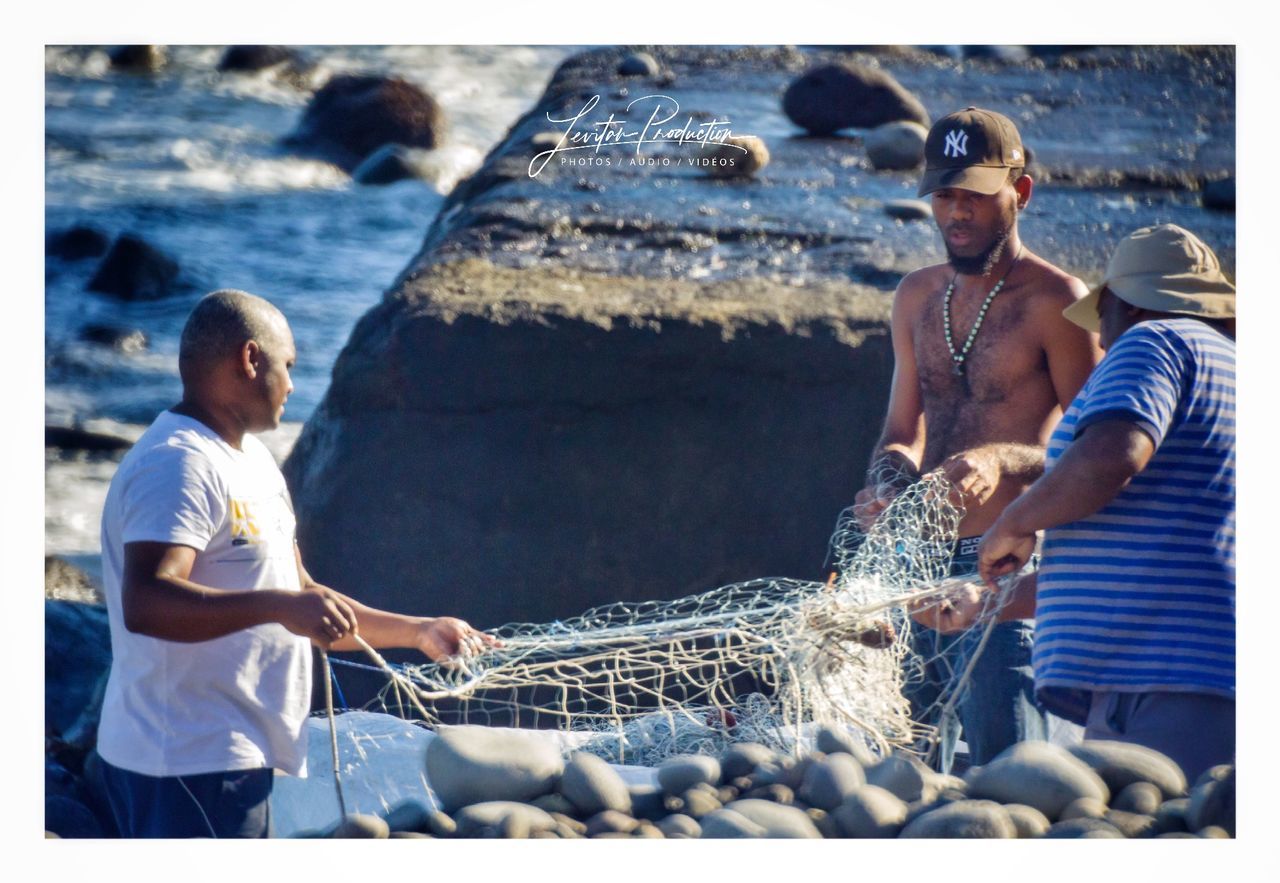 water, real people, men, sea, transfer print, nature, auto post production filter, day, people, two people, casual clothing, three quarter length, leisure activity, young men, lifestyles, rock, outdoors, togetherness, beach, fishing industry