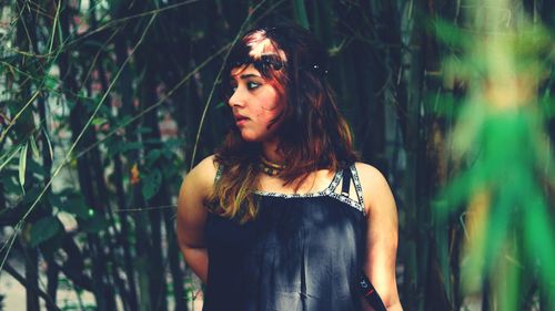 Beautiful young woman standing against trees