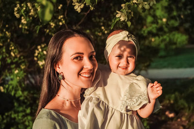 Portrait of young woman standing against trees