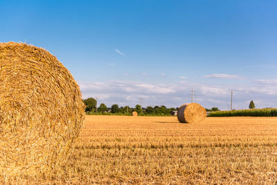 Hay bales on field against sky