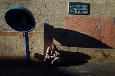 Full length of young woman sitting on mobile phone