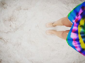 Low section of woman standing on sand