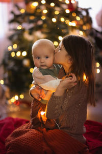 Baby and her older sister on the background of the christmas tree, the concept of christmas 