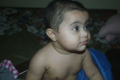 Cute baby girl wrapped in towel on bed at home