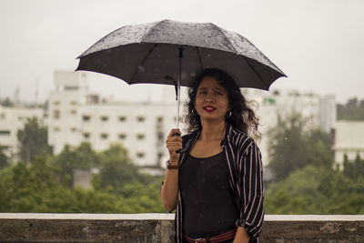 Portrait of man holding umbrella standing during rainy season