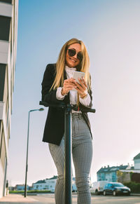 Woman wearing sunglasses standing against sky