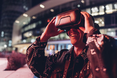 Young man using virtual reality headset at night in city