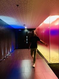 Full length of woman standing in illuminated corridor