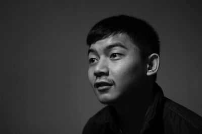 Close-up of thoughtful man looking away against gray background