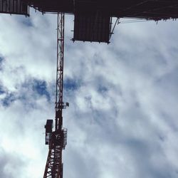 Low angle view of crane against cloudy sky