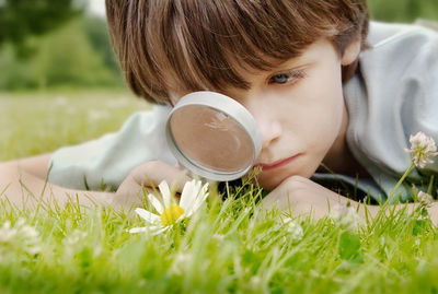 Close-up of boy looking flowers through magnifying glass