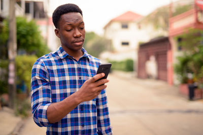 Young man using mobile phone in city