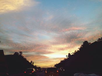 Cars on road against cloudy sky