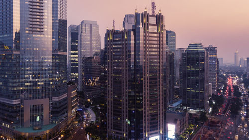 Illuminated buildings in city against sky