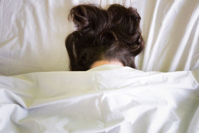 Close-up of woman under blanket on bed