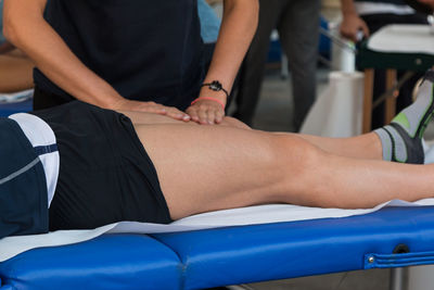 Midsection of man giving massage to athlete lying on bed