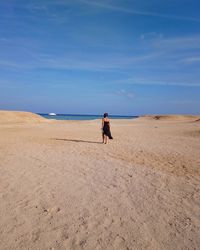 Rear view of woman walking on sand at beach