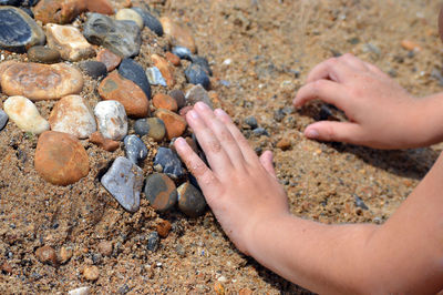Close-up of hands on rocks at beach