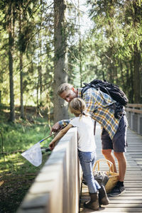 Father with backpack talking to daughter on footbridge in forest