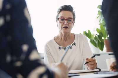 Senior businesswoman holding pen during meeting in office