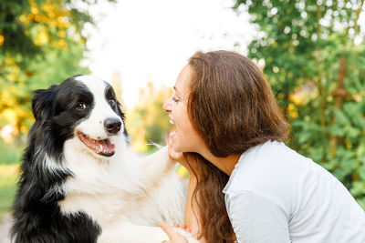 Woman embracing dog snout at park