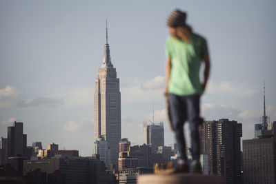 Man standing on column with empire state building in background