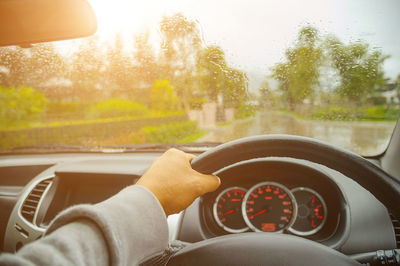 Cropped hand of person driving car during rainy season