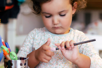 Left-handed little girl sharpening a pencil.