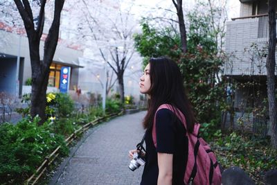 Side view of young woman against plants