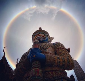 Low angle view of statue against rainbow in sky