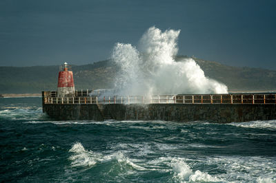 Lighthouse by sea against sky