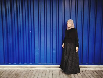 Woman standing against blue wall