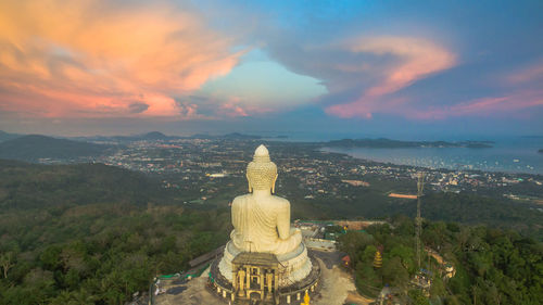 Rear view of giant buddha statue against cloudy sky