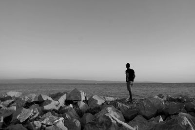 Rear view of man standing on beach against clear sky