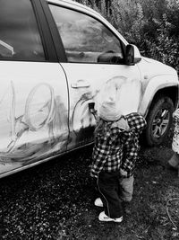 Rear view of boy standing by car