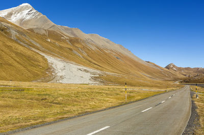 Road by mountain against sky