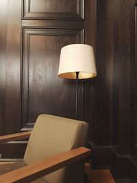 Empty armchair and floor lamp against wooden wall at home