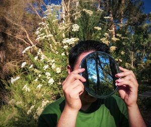 Portrait of woman photographing through tree