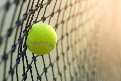 Close-up of green tennis ball on net