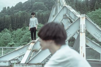 REAR VIEW OF MAN AND WOMAN STANDING BY RAILING AGAINST PLANTS