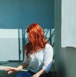 Woman sitting by wall