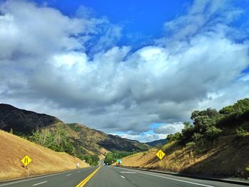 Empty road along mountain landscape against cumulus cloud sky