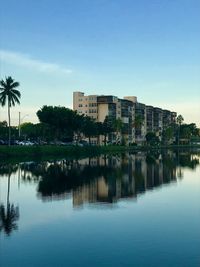 Buildings by lake against sky in city
