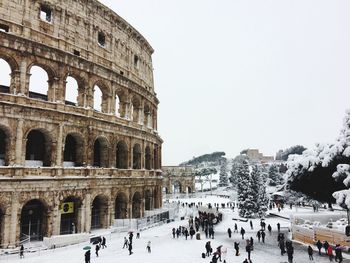 People by coliseum against sky during winter