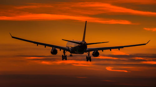 Airplane flying in sky at sunset