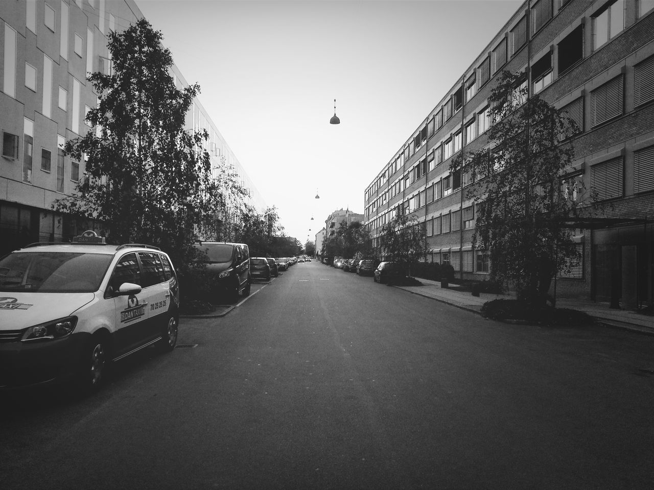 building exterior, architecture, built structure, transportation, the way forward, street, city, car, diminishing perspective, land vehicle, mode of transport, building, road, street light, residential building, residential structure, clear sky, vanishing point, in a row, city street