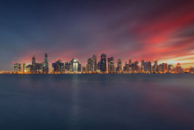 Illuminated modern buildings in city against sky