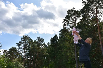 Low angle view of friends standing by tree against sky