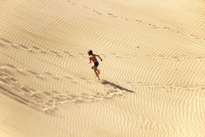 High angle view of boy running on sand 